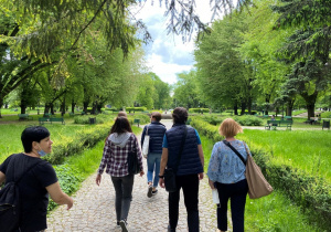 Uczestnicy wycieczki idą aleją Parku Staromiejskiego pośród wiosennej zieleni