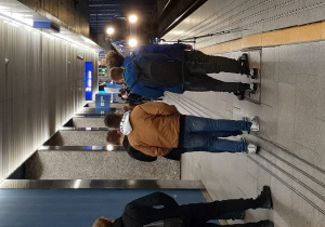 Grupa uczniów na peronie kolejowym oczekuje na nadjeżdżający pociąg ekspress