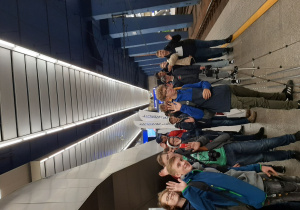 Grupa uczniów na peronie kolejowym oczekuje na pociąg