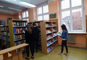 Wnętrze biblioteki szkolnej. Uczniowie dokonują wyboru książek i czasopism.